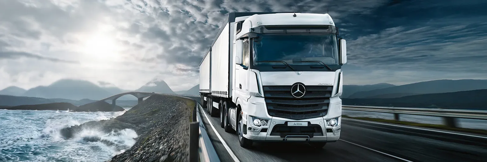 White Mercedes-Benz Actros long-distance truck travelling on a coastal road